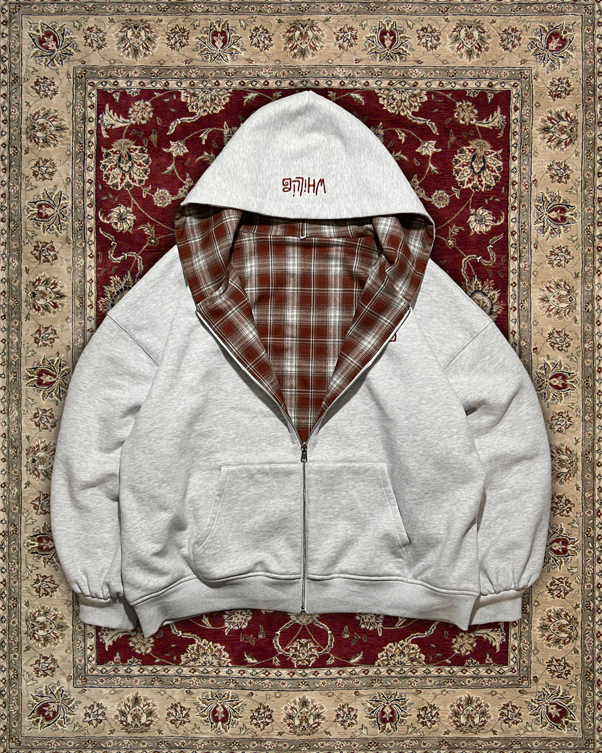 Gray hoodie with plaid lining on a patterned rug